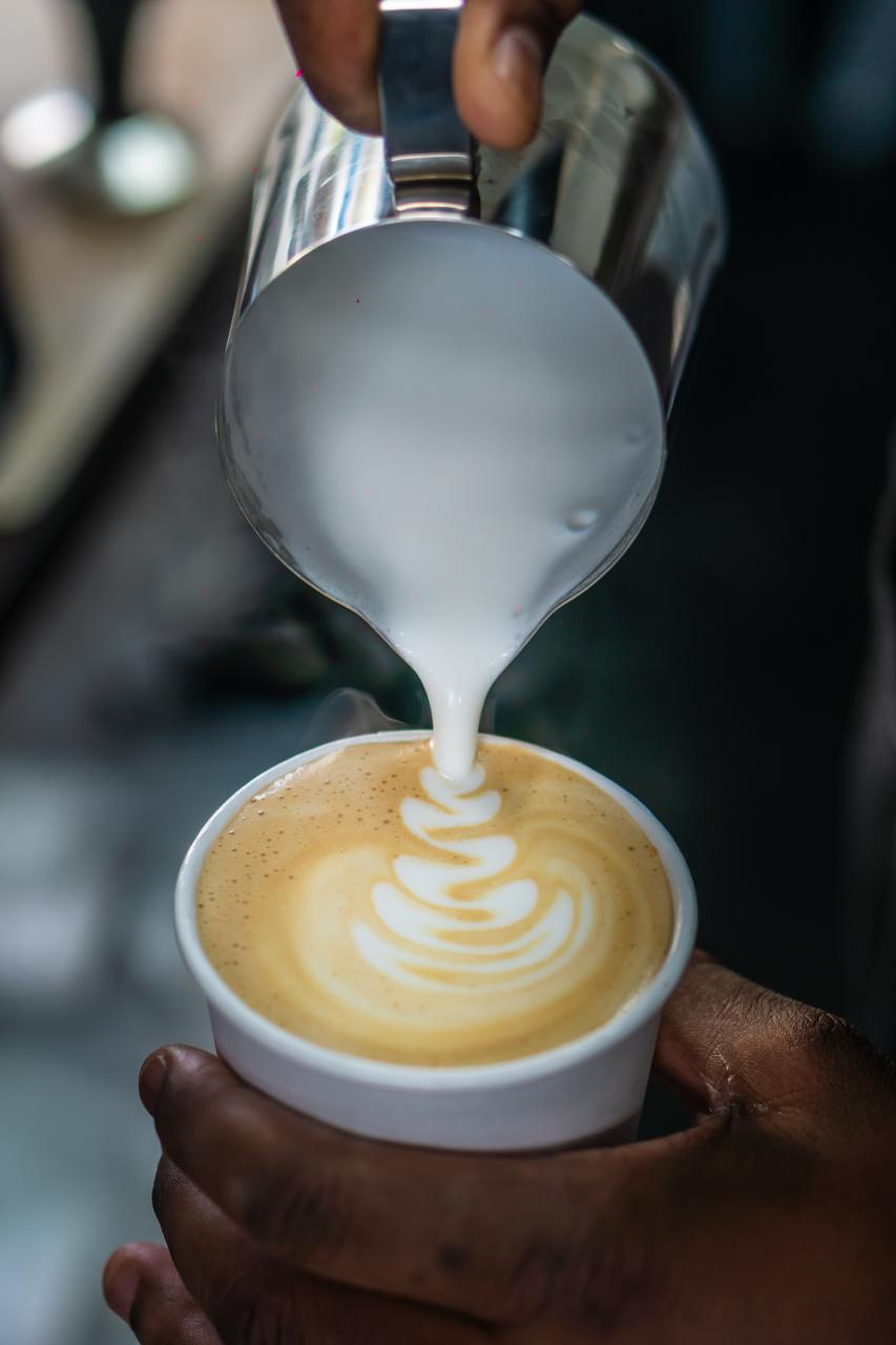 Barista pouring latte art into a BRU. cup